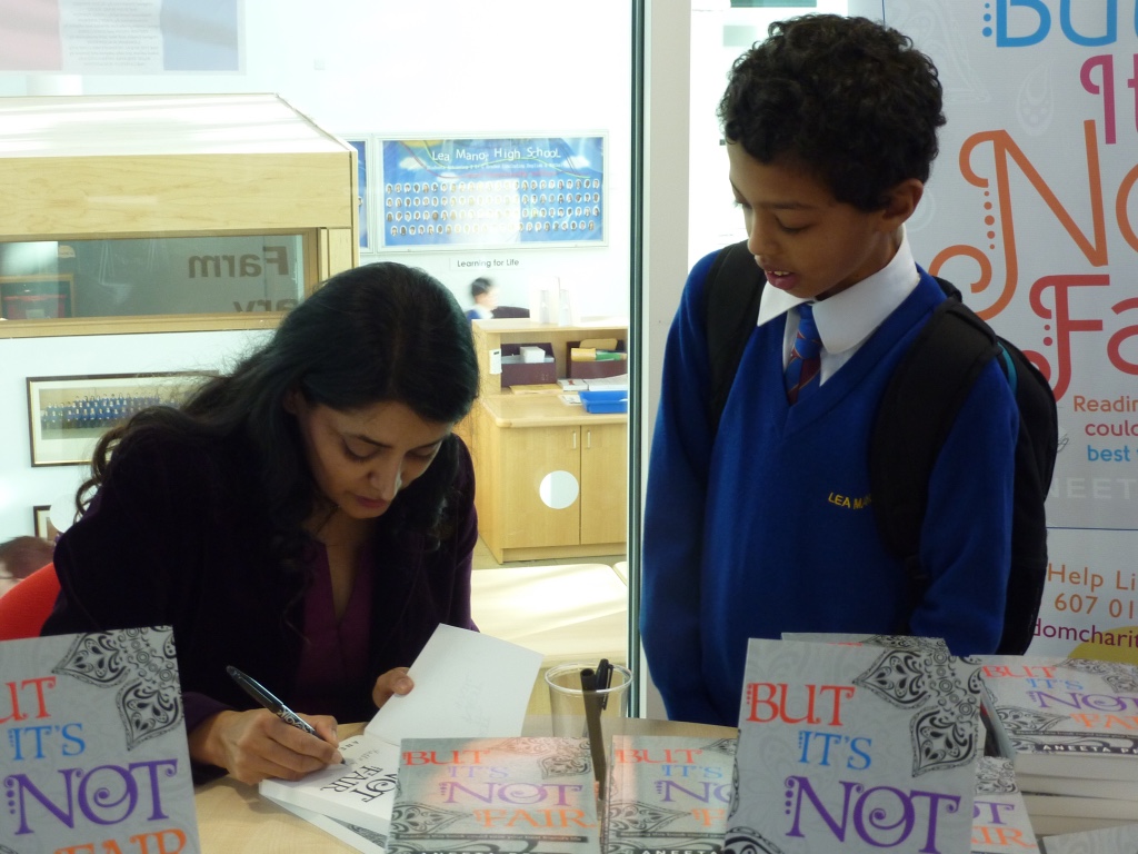 A pupil receiving a signed copy of But It's Not Fair from Aneeta Prem