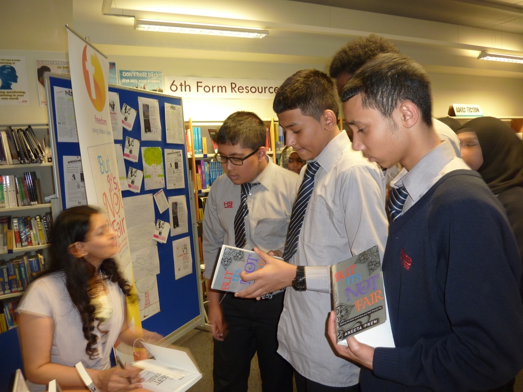 Pupils holding copies of But It's Not Fair in a school library